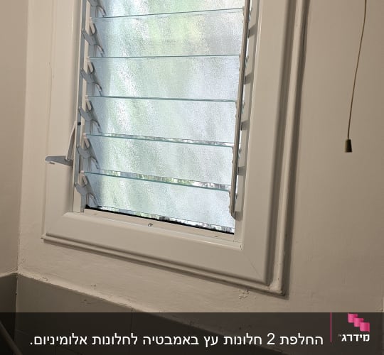 חלון עם תריסי אלומיניום פתוחים חלקית